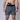 Person wearing grey shorts with a gun holster on a plain background