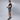 Person holding a gun while wearing grey shorts with a plain background