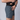 The image shows a side view of a person wearing dark grey athletic shorts and placing a smartphone into the front pocket.
