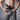 A close-up of a man pulling open the waistband of crater grey chinos to show the built-in drawstring waistband and a black inside-the-waistband holster with a handgun.