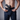 A close-up of a man pulling open the waistband of navy blue chinos to show the built-in drawstring waistband and a black inside-the-waistband holster with a handgun.