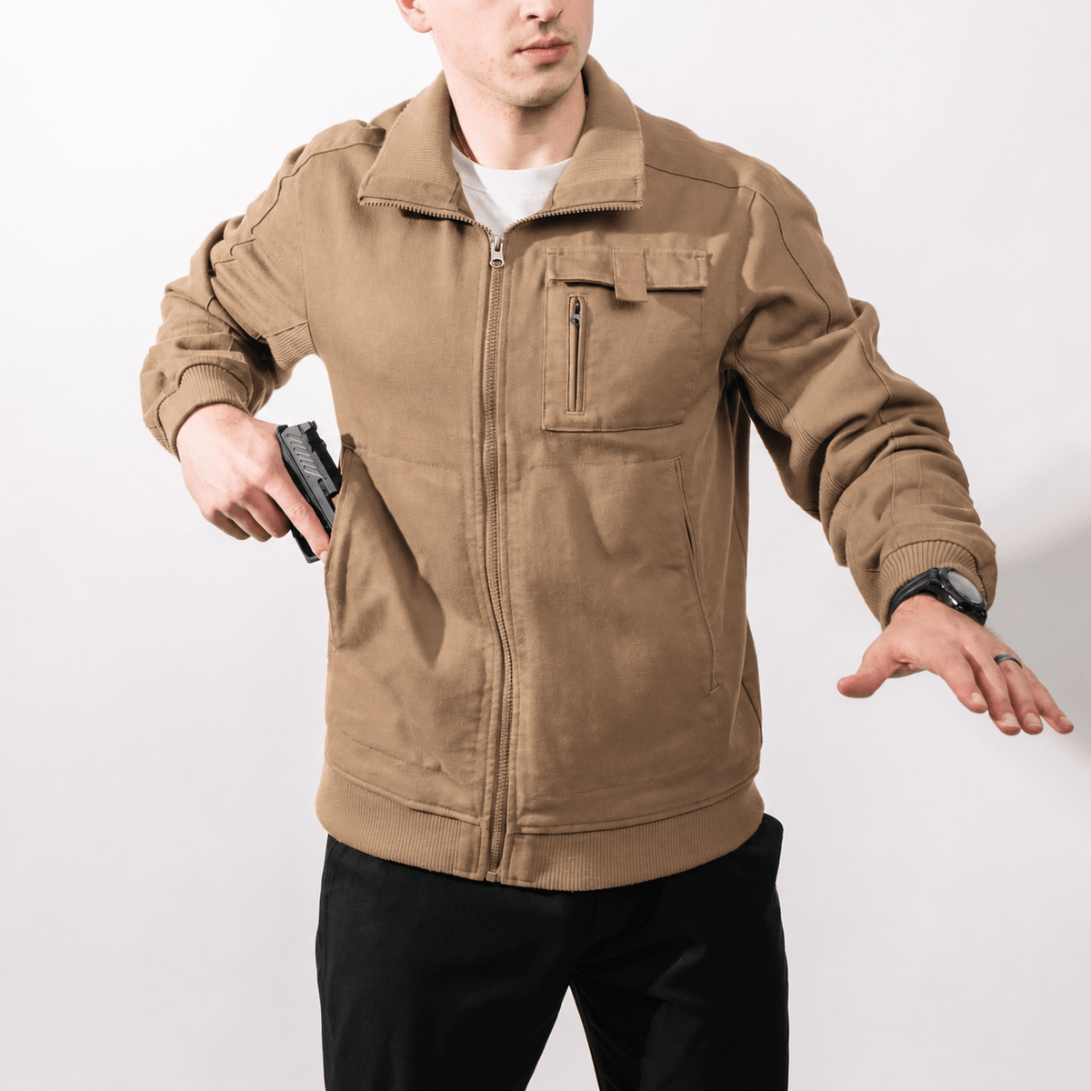 Utility Bomber Jacket - Field Tan - drawing a pistol through the pass-through side pocket with the jacket zipped
