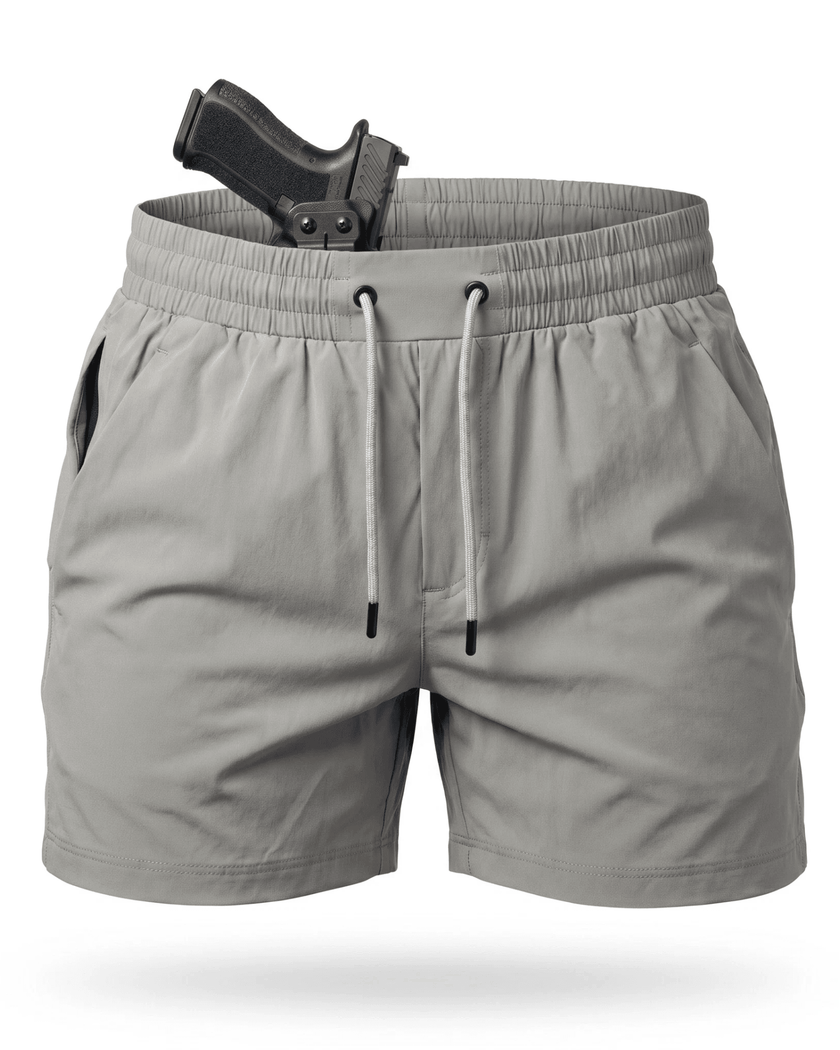 Light gray athletic shorts with a drawstring waist and side pockets, shown on a white background with a black handgun partially tucked into the back waistband.