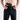 A close-up of a man pulling the waistband of black Constantine Carry Pants open to show an appendix holster with a handgun and spare magazine carried inside the waistband.