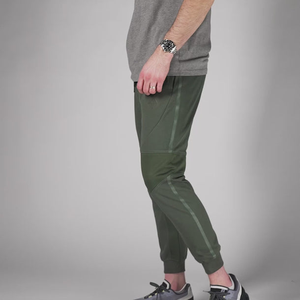 Studio video of model wearing green concealed carry joggers. #color_carbon-grey